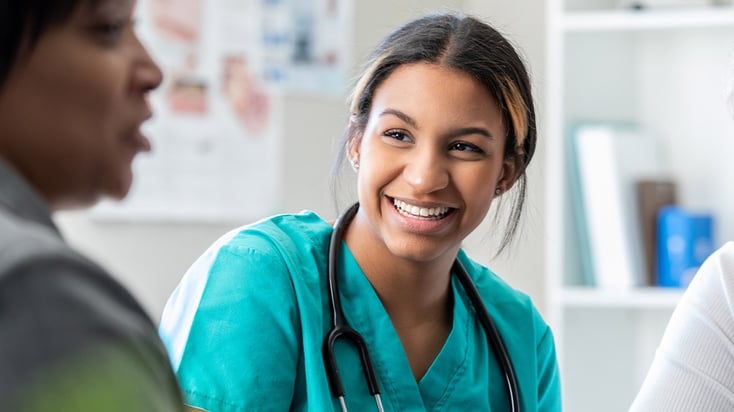 Nurse smiles while interacting with patient and shows joy at her job