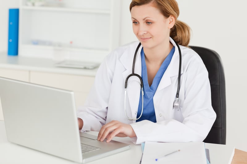 Attractive female doctor working on her laptop in her office-1