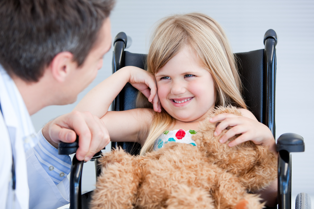 Laughing little girl sitting on the wheelchair at the hospital