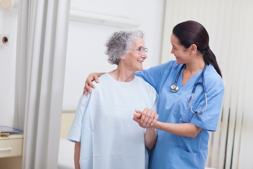 Nurse and a patient standing in hospital ward