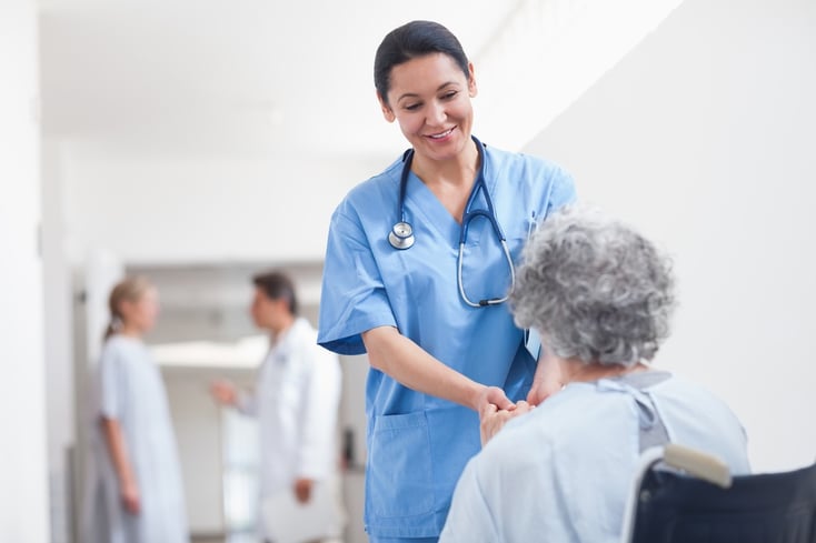 Nurse standing next to a patient while holding her hands in hospital ward.jpeg