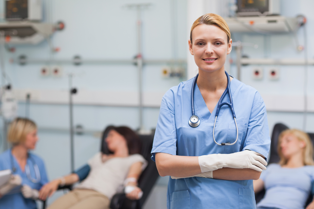 Nurse standing with arms crossed next to patients in hospital ward