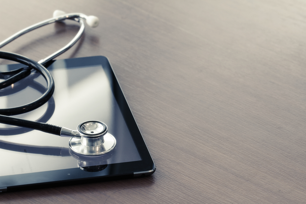 Studio macro of a stethoscope and digital tablet with shallow DOF evenly matched abstract on wood table background copy space-1