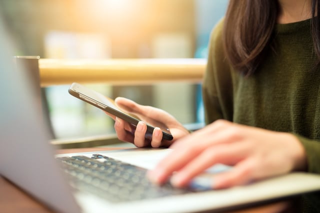 Woman connecting cellphone and laptop computer.jpeg