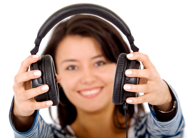 girl holding headphones and smiling isolated over a white background
