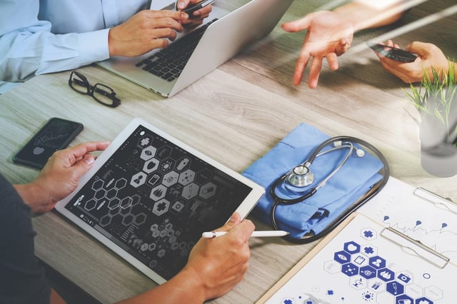 top view of Medicine doctor hand working with modern computer and digital pro tablet with his team with digital medical diagram on wooden desk as medical concept.jpeg