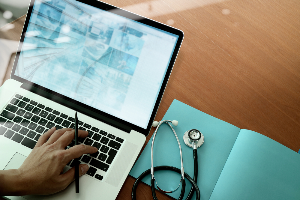 top view of Medicine doctor hand working with modern computer and smart phone on wooden desk as medical concept