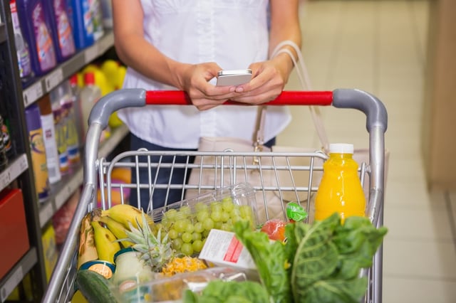 woman buy products and texting at supermarket.jpeg